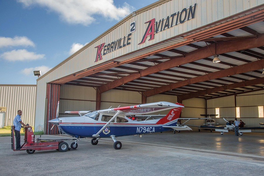 worker tows airplane into hanger