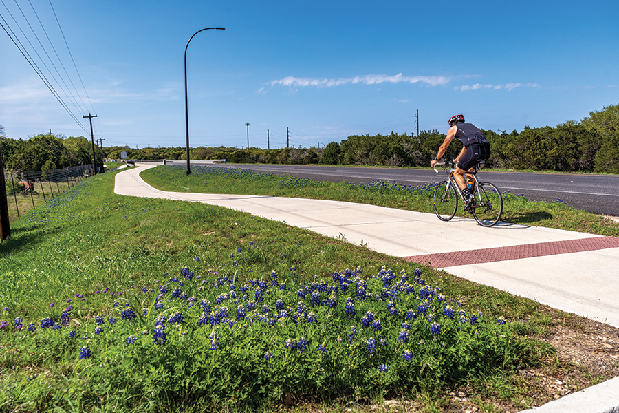 cyclist rides all sidewalk with road in background