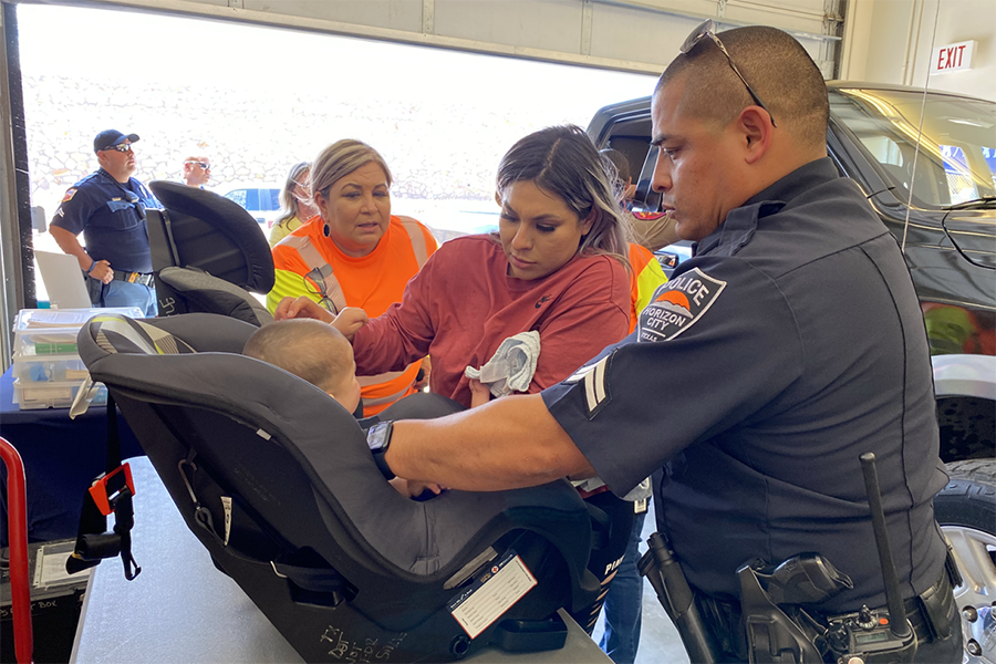 A police officer helps a parent with a car seat