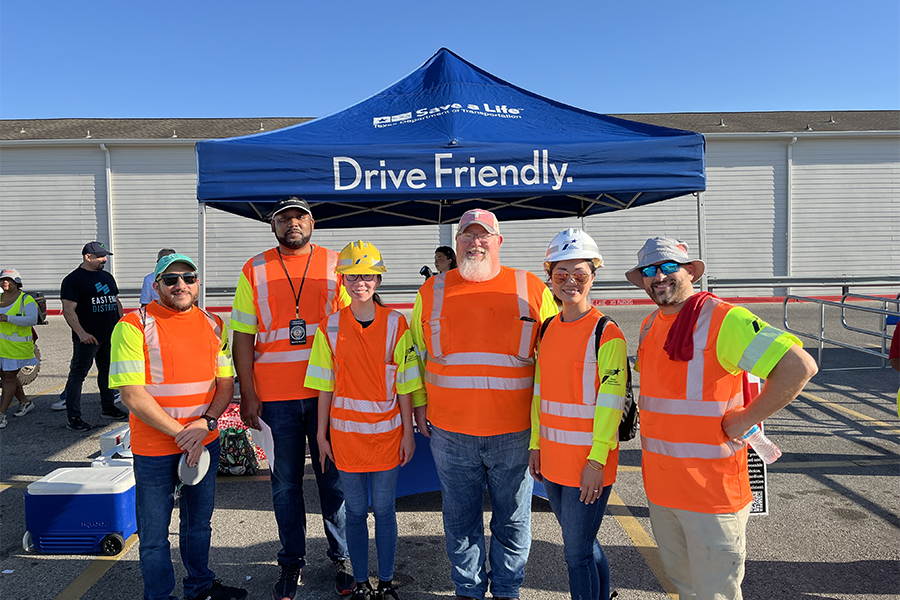 Houston traffic safety coalition members wearing safety vests, posed smiling under canopy.