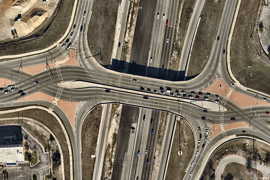 Aerial view of a diverging diamond interchange with traffic briefly crossing to the left between ramps and a divided highway.