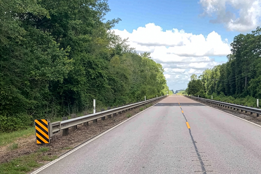 Una carretera rural con vallas de protección y alcantarilla.