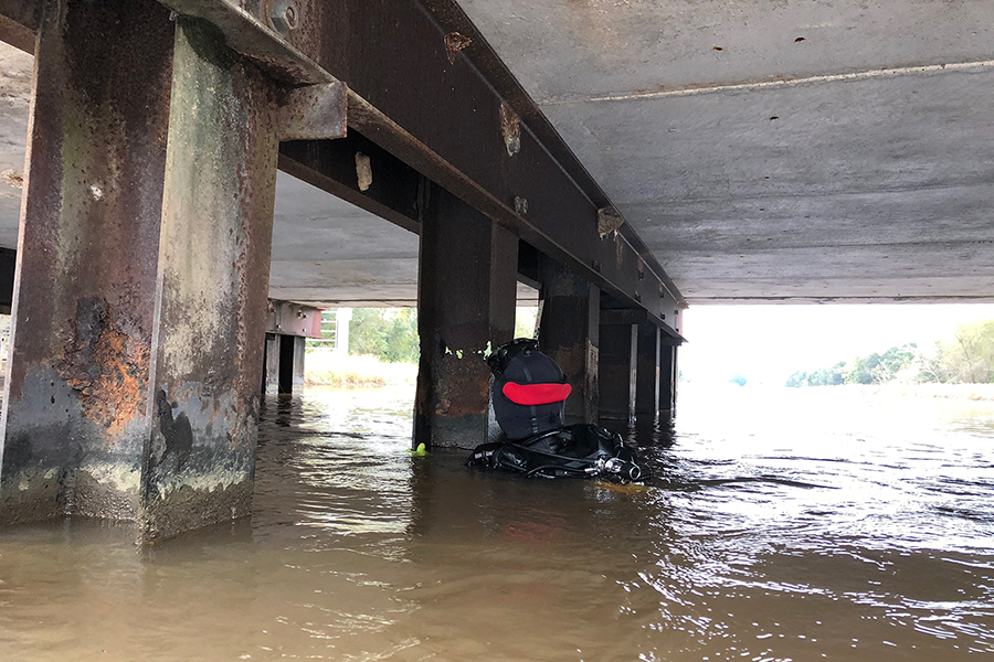 Un buceador de TxDOT realiza una inspección submarina de los soportes del puente.