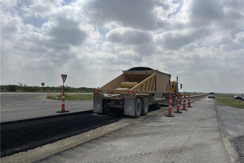 paving truck putting down asphalt on roadway