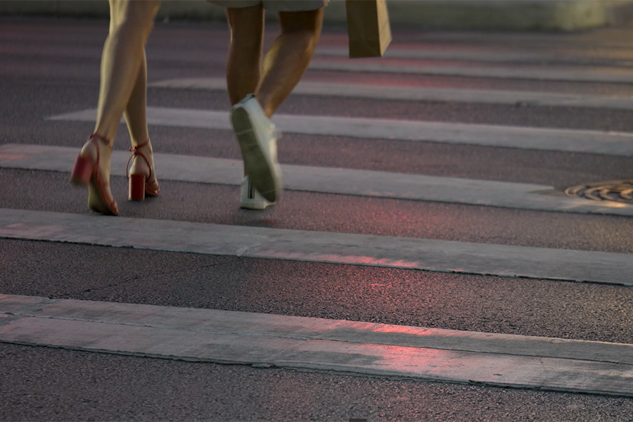 La gente cruza la calle por la noche usando un paso de peatones.