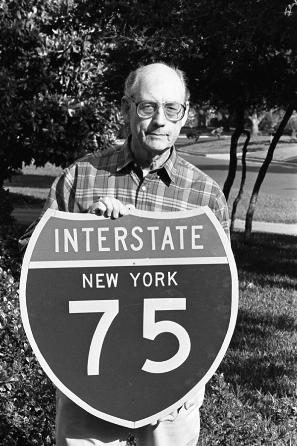 Black and whit photo of TxDOT employee Richard Oliver holding a shield sign for Interstate 75.