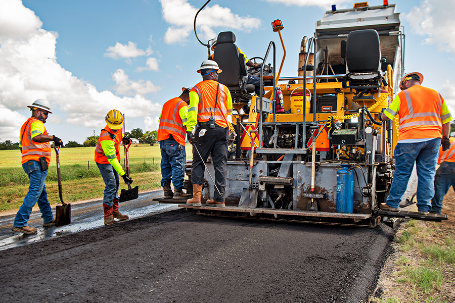 Maintenance workers on filling machine repairing asphalt