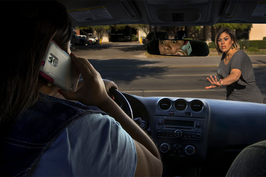 Distracted driver on cell phone approaching woman in crosswalk