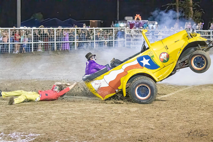 Rodeo clown being pulled behind a vehicle driven by another rodeo clown.