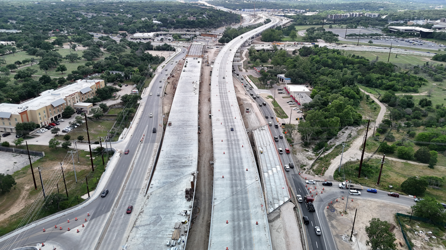 With the westbound US 290 mainlane bridge temporarily supporting eastbound traffic, Oak Hill Parkway crews make progress on the future eastbound US 290 mainlane bridge next to it.  Crews recently poured the concrete bridge deck for several spans of this bridge east of William Cannon Drive as they continue to place beams for spans to the west.  May 2025